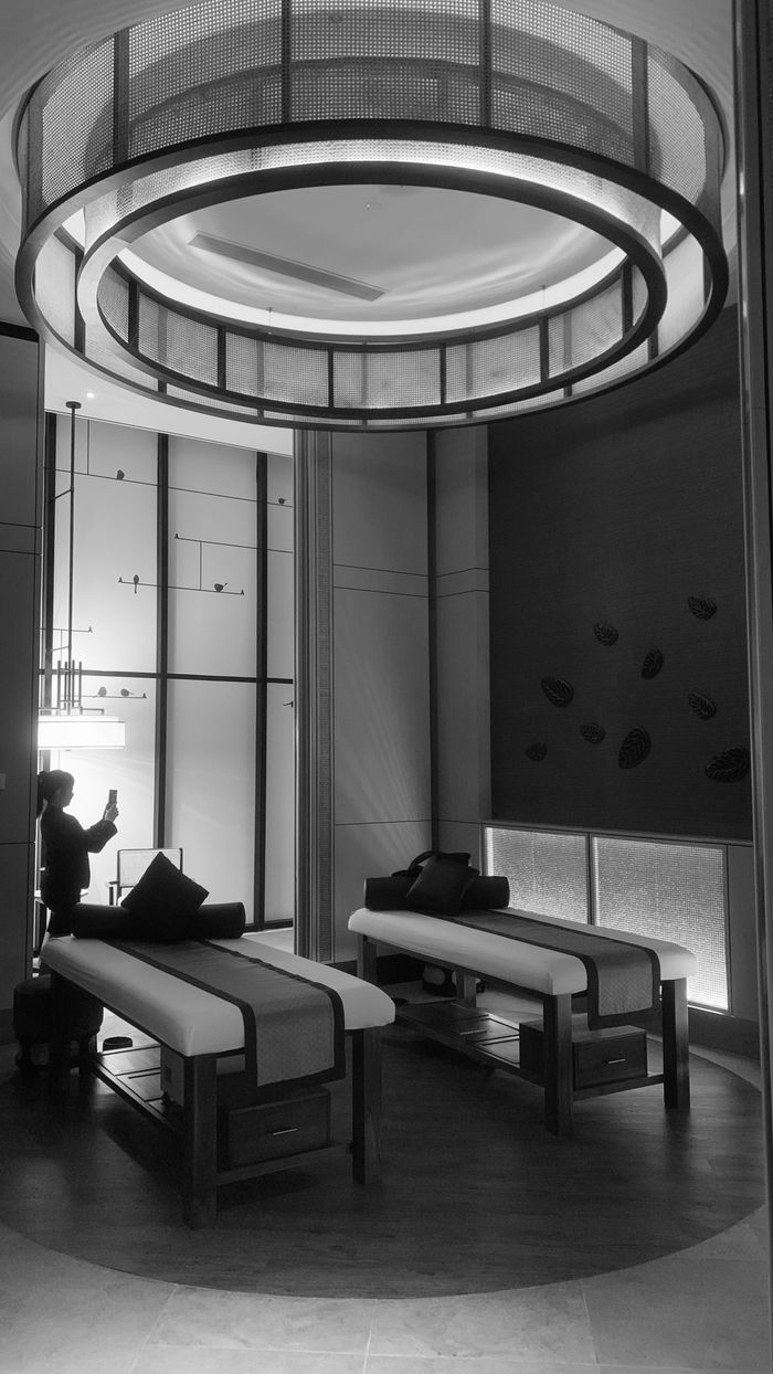 Chic black and white spa room with modern lighting and massage tables, exuding luxury and tranquility.