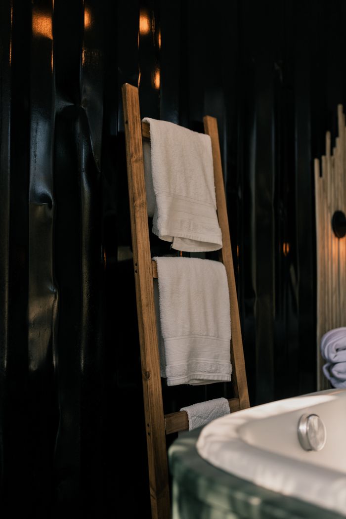 Stylish bathroom featuring a wooden ladder with white towels in a dimly lit setting.