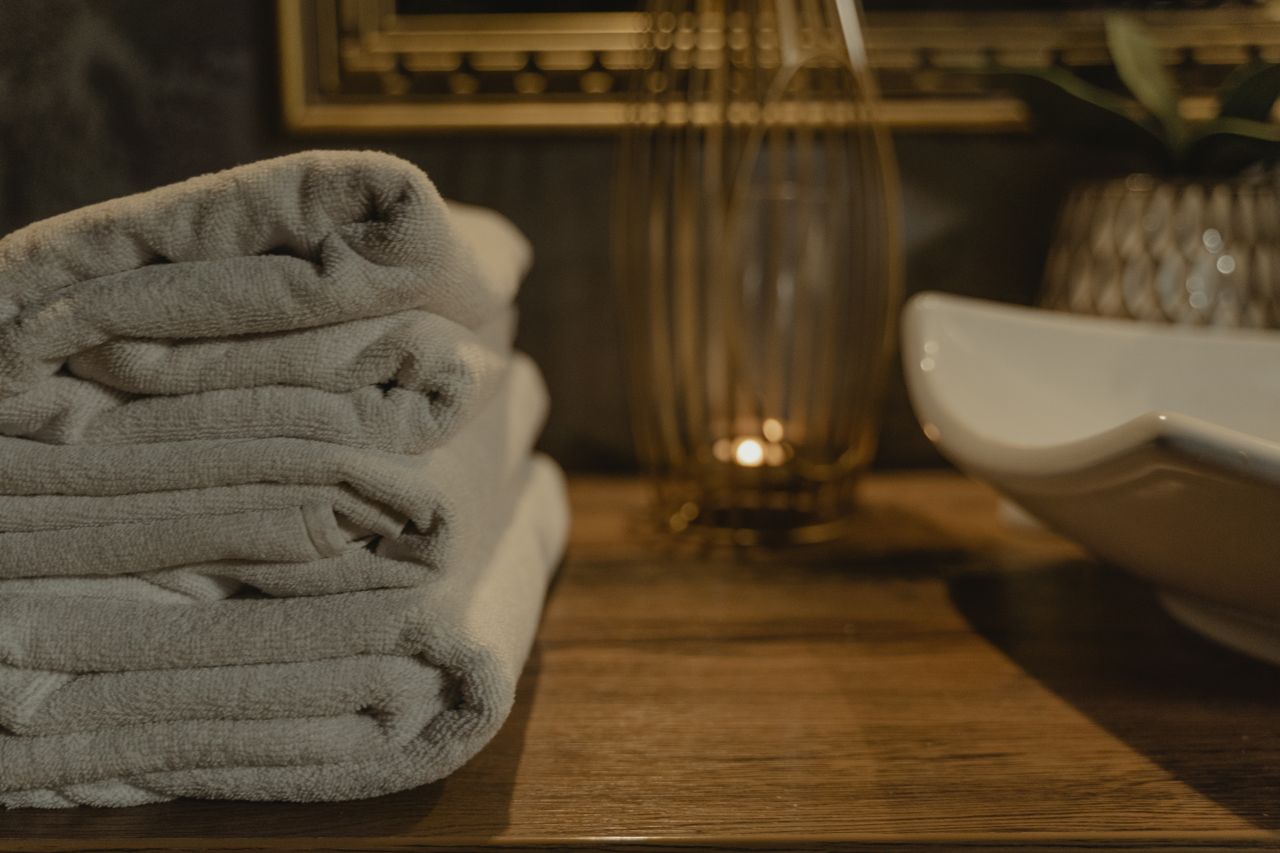 Elegant white towels neatly stacked in a cozy bathroom ambiance with soft lighting.