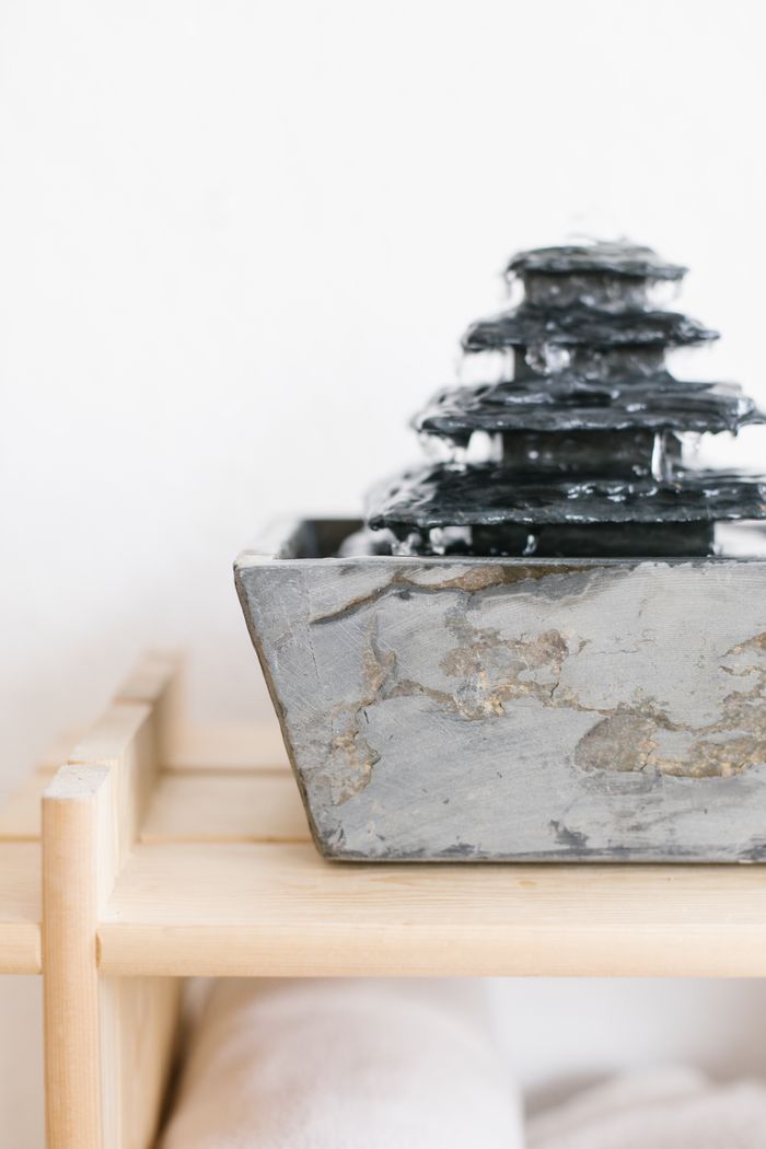 Elegant marble desktop water fountain on wooden shelf, perfect for minimalist home decor.