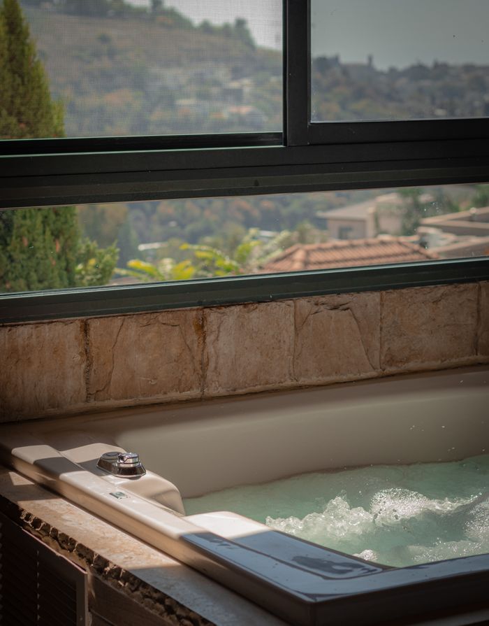 Luxurious indoor bathtub with a scenic view of hills through a large window, perfect for relaxation.